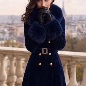 May include: A long navy blue velvet coat featuring a large faux fur collar and matching fur cuffs. The coat is double-breasted with gold-toned buttons and includes a matching fabric belt secured by a rectangular gold-toned buckle with crystal accents.