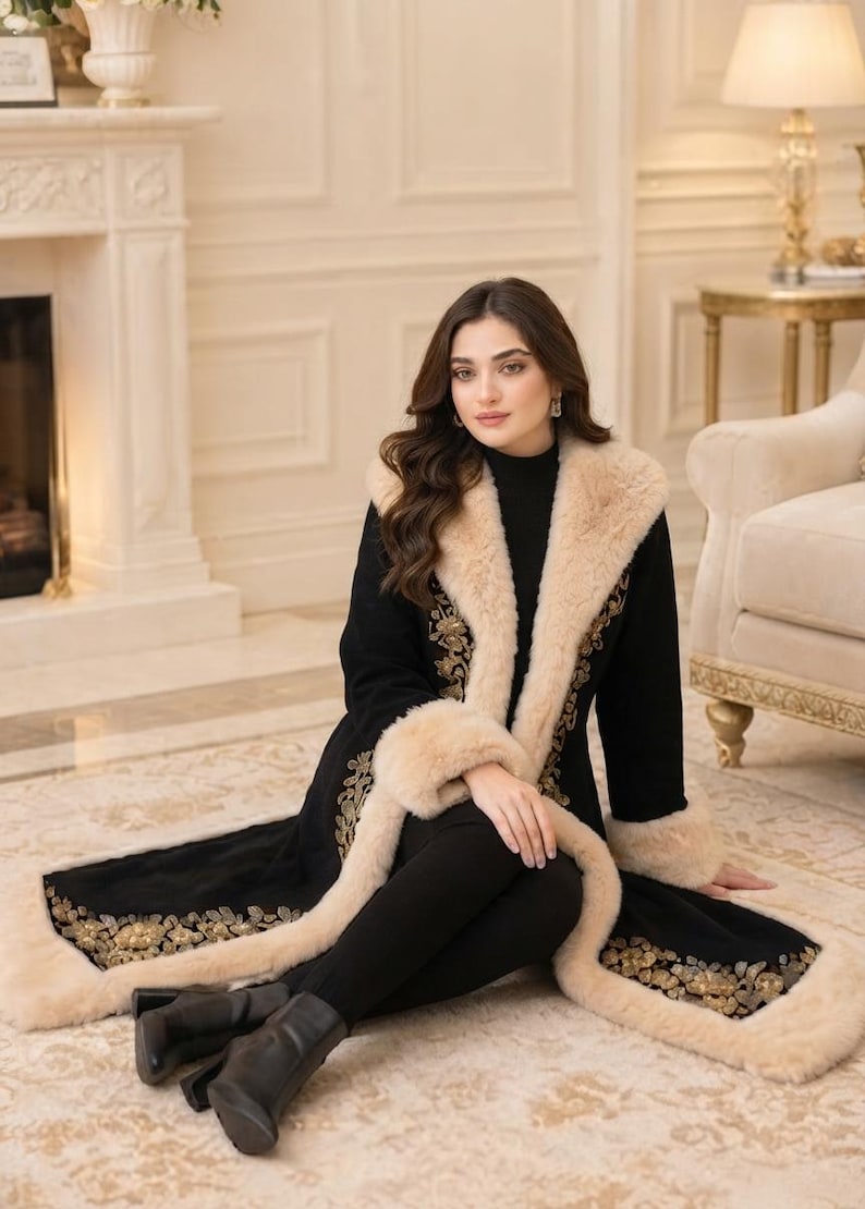 Pu&ograve; includere: Un cappotto nero a maniche lunghe con ampio colletto e polsini in pelliccia sintetica beige, decorato con intricati ricami floreali dorati lungo i bordi anteriori e l'orlo, abbinato a leggings neri e stivaletti neri.