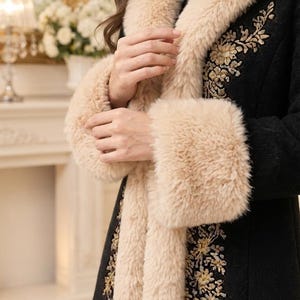 Pu&ograve; includere: Un cappotto nero con un folto colletto in pelliccia sintetica beige e polsini in pelliccia sintetica abbinati. Il cappotto &egrave; decorato con intricati ricami floreali dorati sui pannelli frontali, che si estendono dallo scollo al fondo.