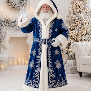 May include: A floor-length royal blue velvet coat with a hood, featuring thick white faux fur trim on the cuffs, hem, and front opening. The coat is decorated with intricate silver embroidery and snowflake patterns, secured by a matching belt.