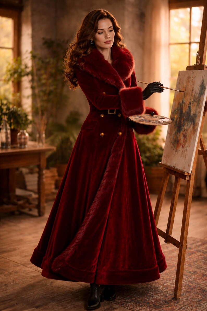 May include: A floor-length deep red velvet coat featuring a wide faux fur collar and matching faux fur cuffs. The coat is double-breasted with gold-toned buttons, a belted waist, and a full, flared skirt silhouette that reaches the floor.
