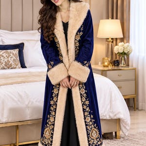May include: A long, deep blue velvet coat featuring a thick, beige faux fur trim along the collar, front opening, and sleeve cuffs. The coat is decorated with intricate gold floral embroidery patterns running vertically along the front panels.