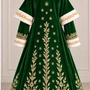 May include: A floor-length dark green velvet coat featuring a white faux fur collar, cuffs, and hem. The back is decorated with gold embroidered leaf patterns and snowflake motifs. The sleeves have layered cuffs with gold embroidery.