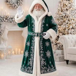 May include: A floor-length dark green velvet coat with a white faux fur hood, cuffs, and hem. The coat features intricate silver embroidery in snowflake and scroll patterns, a matching belt with a silver buckle, and white gloves.
