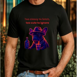 Puede incluir: Camiseta negra con un gráfico de un bulldog francés con un sombrero fedora y bebiendo de un vaso con pajita. El texto "Too classy to fetch, too cute to ignore" está encima del perro.