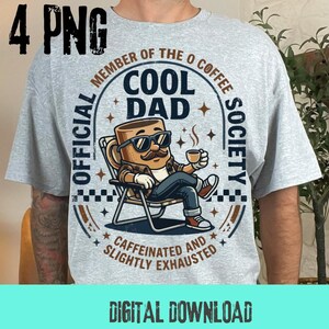 Op de afbeelding: Lichtgrijs t-shirt met een afbeelding van een koffiekopkarakter met een zonnebril en een kopje koffie, zittend in een stoel. De tekst luidt "COOL DAD" en "OFFICIAL MEMBER OF THE COFFEE SOCIETY". De zin "CAFFEINATED AND SLIGHTLY EXHAUSTED" is ook aanwezig.