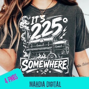 May include: A charcoal gray t-shirt featuring a white graphic print of an offset smoker grill with smoke rising from the chimney. The text reads IT'S 225° SOMEWHERE above and below the grill illustration, with a small spatula and fork icon below.