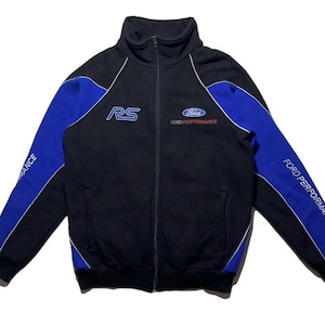 May include: Black zip-up jacket with blue sleeves and white trim. The jacket features the Ford Performance logo and the letters "RS" on the chest. The sleeves have the words "Ford Performance" printed on them.