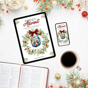 Könnte beinhalten: Ein Tablet und ein Smartphone zeigen das Cover eines Buches mit dem Titel „Abiding In Advent“. Das Cover zeigt eine Weihnachtskugel mit einer Krippenszene im Inneren, umgeben von einem Kranz und einer roten Schleife. Eine Tasse Kaffee und ein offenes Buch sind ebenfalls im Bild.