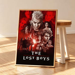 May include: A rectangular poster for the film The Lost Boys featuring a collage of character portraits in shades of red and black. The central figure has spiky hair, and the title text THE LOST BOYS appears in white at the bottom of the print.