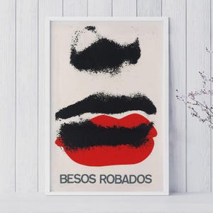 Könnte beinhalten: Ein gerahmter Kunstdruck mit einem abstrakten Design. Schwarze Pinselstriche befinden sich über und unter einem Paar roter Lippen. Die Worte "BESOS ROBADOS" sind unten auf dem Druck in Grau gedruckt.