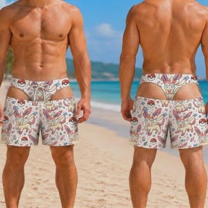 May include: Swim trunks featuring a repeating pattern of the character Sylveon and red and white Poké Balls on a light background. The trunks have a high-cut design with a drawstring waist and a separate, matching patterned piece at the top.