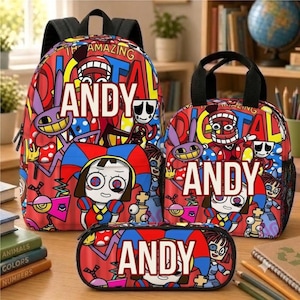 Op de afbeelding: Een set bestaande uit een rugzak, een lunchtas en een etui met een felrode achtergrond, een kleurrijke cartoonprint en de naam ANDY in grote witte letters op de voorzijde van elk item in deze bijpassende set.