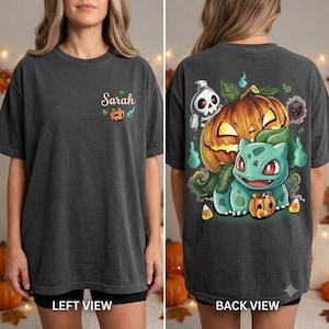 Könnte beinhalten: Ein anthrazitfarbenes T-Shirt mit einer kleinen Grafik auf der linken Brustseite, die den Namen Sarah und einen winzigen Kürbis zeigt. Die Rückseite zeigt eine große, farbenfrohe Illustration eines grünen Wesens, eines leuchtenden Kürbisses und eines Geistes.