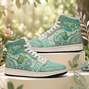 Puede incluir: Un par de zapatillas altas en verde claro y azul cerceta con un estampado gráfico de una pequeña criatura verde con un bulbo en la espalda. Los zapatos tienen cordones blancos, entresuelas blancas y suelas negras, decoradas con hojas y pétalos.