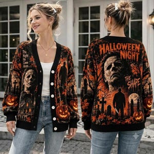 May include: A black button-down cardigan featuring an orange and black Halloween-themed graphic print. The design includes a graveyard scene, pumpkins, and the face of Michael Myers with the text "Halloween Night" and "The Shape" on the back.