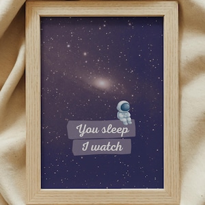 Peut inclure: Impression encadrée représentant un ciel étoilé bleu foncé avec un petit astronaute. Le texte "You sleep I watch" est affiché sur une bannière violet clair. Le cadre est en bois clair.