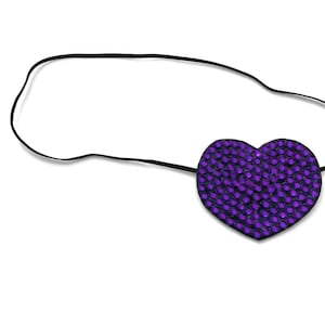 May include: A heart-shaped eye patch with a purple, jewel-like design. The patch is attached to a black elastic band. The eye patch is designed to cover one eye.