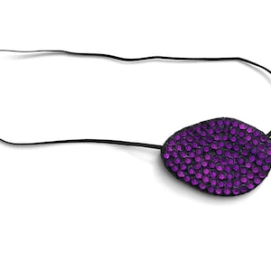 May include: A decorative eye patch with a black strap. The patch is oval-shaped and covered in small, sparkling purple rhinestones. The background is plain white.