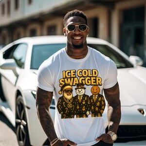 May include: White t-shirt with the text "ICE COLD SWAGGER" in gold lettering. The shirt features a graphic of three gingerbread men dressed in suits. The person in the image is wearing sunglasses and a gold watch.