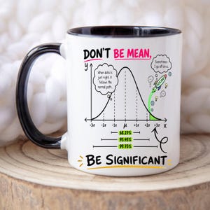 May include: A white ceramic mug with a black handle and interior rim. The mug features a black bell curve graph with the text "DON'T BE MEAN, BE SIGNIFICANT". It includes a rocket graphic labeled "OUTLIER!" and statistical data points.