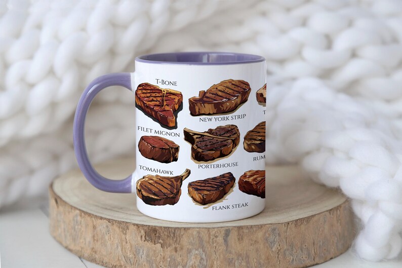 May include: White ceramic mug with a purple interior and handle, featuring illustrations of various steak cuts like T-bone, filet mignon, and New York strip. The mug is set on a wooden surface against a soft, white background.