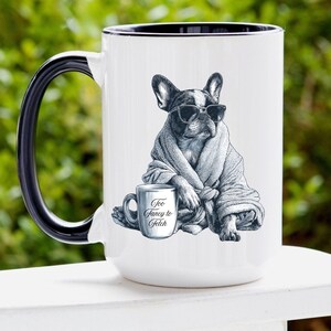 May include: White ceramic mug with a black handle and rim. The mug features a black and white illustration of a French Bulldog wearing sunglasses and a robe, with a smaller mug that says "Too Fancy to Fetch."