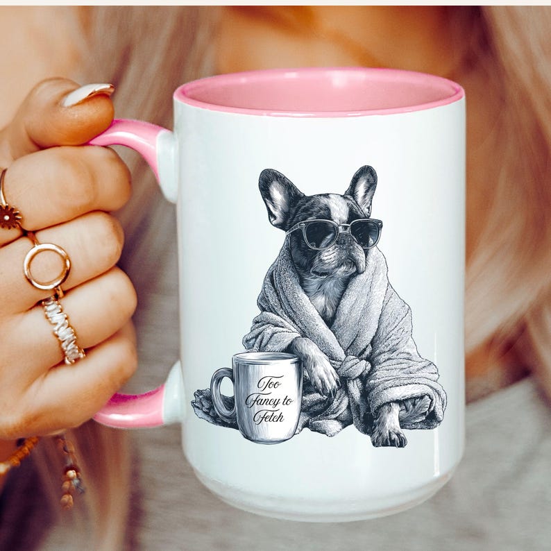 May include: White ceramic mug with a pink interior and handle. The mug features a black and white illustration of a French Bulldog wearing sunglasses and a robe, with a small mug that says "Too Fancy to Fetch."
