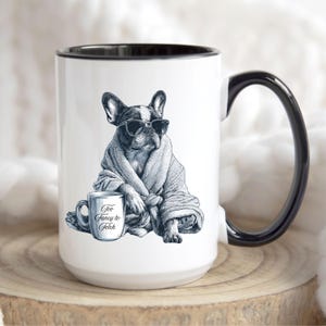 May include: White ceramic mug with a black interior and handle. The mug features a detailed illustration of a French Bulldog wearing sunglasses and a robe, holding a mug that says "Too Fancy to Fetch".