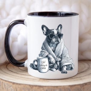 May include: White ceramic mug with a black interior and handle. The mug features a black and white illustration of a French Bulldog wearing sunglasses and a robe. A smaller mug with the text "Too Fancy to Fetch" is also in the image.