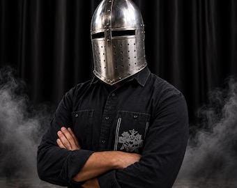 May include: A polished steel knight helmet featuring a pointed top, a horizontal eye slit, and a series of small ventilation holes along the lower faceplate. The helmet is constructed with visible metal rivets along the seams and edges.