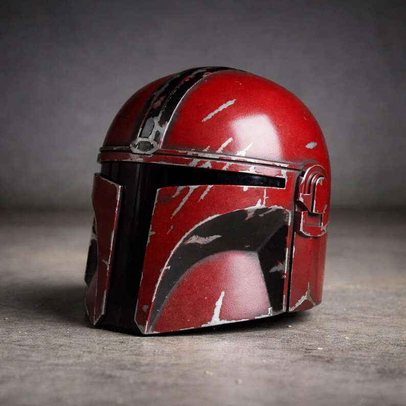 May include: A weathered red and black helmet with silver accents. The helmet has a distinctive design with a visor and a top stripe. The surface shows signs of wear, giving it a battle-worn appearance. The helmet is likely a prop or collectible.