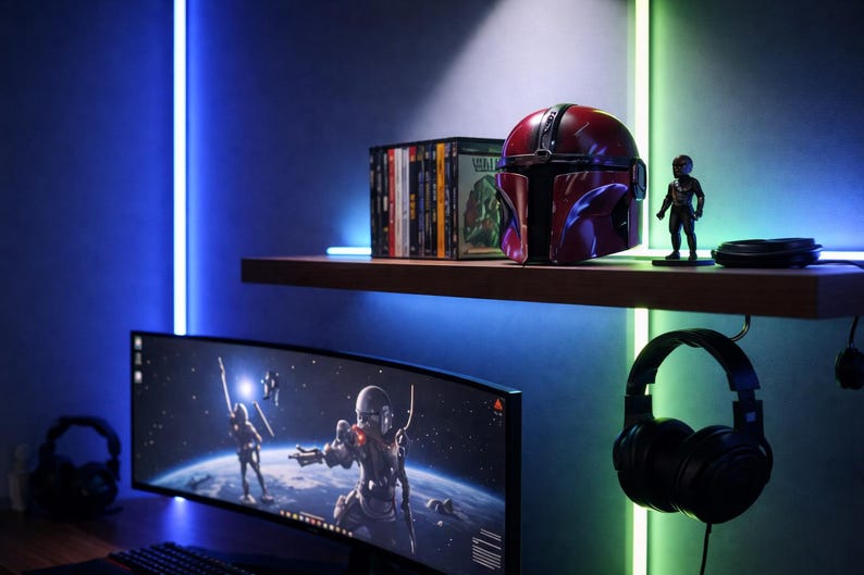 May include: A gaming setup featuring a curved monitor displaying a space scene, a Mandalorian helmet, and a small figurine. The setup includes a shelf with DVDs and a pair of black headphones hanging below. The room is illuminated with blue and green LED lights.
