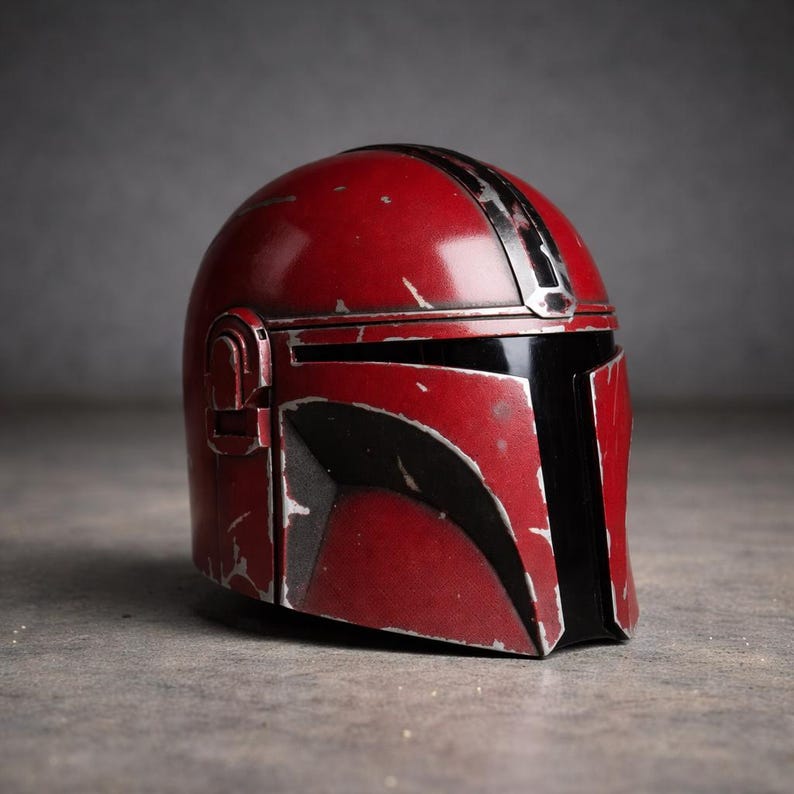 May include: A red and black Mandalorian helmet with a distressed finish. The helmet features a black visor and silver accents. The overall design is reminiscent of a space-themed character.
