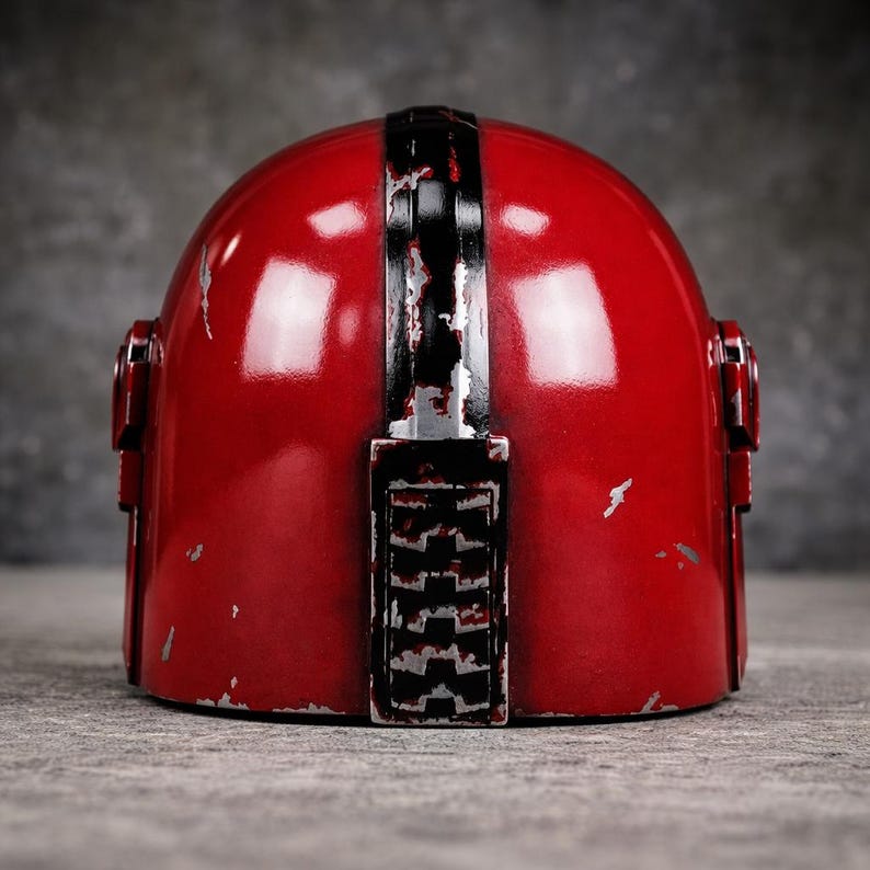 May include: A red helmet with a black stripe down the center and silver accents. The helmet has a weathered appearance with visible scratches and wear. The design includes side details and a lower section with a textured pattern.