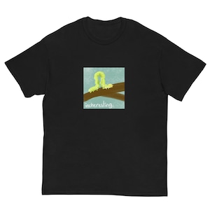 Pode incluir: Camiseta preta com um gráfico quadrado de uma lagarta amarela em um galho marrom sobre um fundo azul. O texto "incheresting" está abaixo. A camiseta é feita de um material macio.