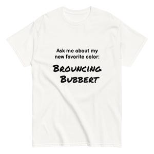 May include: A white t-shirt featuring the text "Ask me about my new favourite colour: BROUNCING BUBBERT" in a bold, black font. The shirt is short-sleeved and appears to be a casual style.