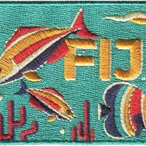 May include: Embroidered patch featuring colorful fish and the word "FIJI" in gold. The patch has a turquoise background with coral-like designs. The fish are in shades of red, yellow, and blue.
