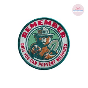 May include: Embroidered patch featuring Smokey Bear in a ranger hat, holding a shovel, with the text "REMEMBER, ONLY YOU CAN PREVENT WILDFIRES." The patch is circular, with a green border and a white background.