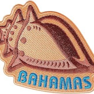 May include: Embroidered patch in the shape of a conch shell with the word "BAHAMAS" in blue letters. The shell is tan with brown and pink accents, and a gold border.