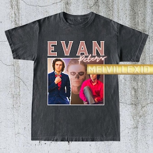 Może przedstawiać: Ciemnoszara koszulka z napisem "EVAN Peters" w różowo-brązowej czcionce. Koszulka przedstawia trzy zdjęcia Evana Petersa. Tekst "MELVILLEXIO" jest wydrukowany w kolorze złotym. Koszulka ma wygląd vintage.