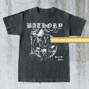 Op de afbeelding: Donkergrijze t-shirt met de bandnaam "BATHORY" in witte gotische letters. De t-shirt toont een witte afbeelding van een figuur in een pentagram, met de tekst "Satan My Master" eronder.