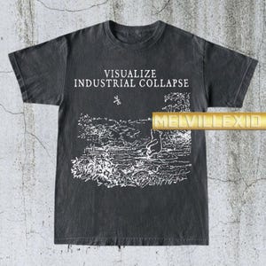 May include: Dark gray t-shirt with the text "VISUALIZE INDUSTRIAL COLLAPSE" in white. The shirt features a white illustration of a bear sitting near a body of water. The brand name "MELVILLEXIO" is printed in gold.