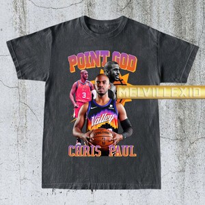 Puede incluir: Camiseta gris oscuro con un gráfico de Chris Paul, jugador de baloncesto, con el texto "POINT GOD" y "CHRIS PAUL". La camiseta también incluye imágenes de Chris Paul con su uniforme de baloncesto.