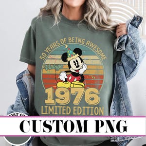 Puede incluir: Camiseta verde oliva con un diseño vintage de Mickey Mouse, un gorro de fiesta y el texto "50 Years of Being Awesome" y "1976 Limited Edition". El diseño tiene un fondo de puesta de sol retro.