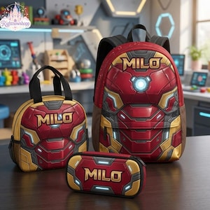 Könnte beinhalten: Ein Set aus Rucksack, Lunchtasche und Federmäppchen in Rot und Gold mit mechanischem Rüstungsdesign, einem leuchtend blauen Brustkern und dem Namen MILO in fetten goldenen Buchstaben auf jedem Teil, in einer strukturierten, robusten Ausführung.