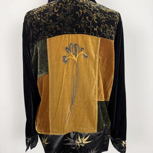 May include: Black velvet jacket with a patchwork design. The back features panels of olive green and gold velvet, with an embroidered floral design. The top and bottom sections have gold floral patterns.