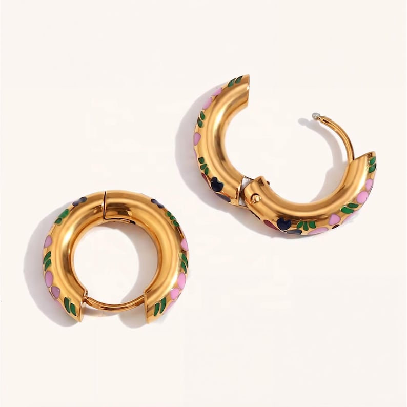 Two thick gold hoop earrings with pink, blue, red, and green enamel floral designs, one open and one closed.