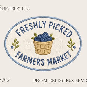 May include: An oval embroidery design featuring a tan woven basket filled with blue blueberries and green leaves. The text reads FRESHLY PICKED FARMERS MARKET in blue. The design includes the text EMBROIDERY FILE and 4 5 6 PES EXP DST DGT HUS JEF VP3 XXX.
