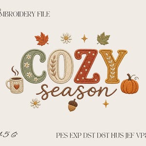 May include: An embroidery file design featuring the text COZY season in colorful, textured lettering. The design includes a steaming mug with a heart, a pumpkin, an acorn, autumn leaves, daisies, and stars. Text at the bottom reads 4 5 6 and PES EXP DST DGT HUS JEF VP3 XXX.